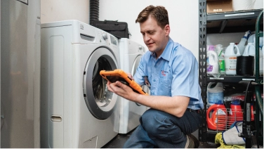 Mr. Appliance repairman inspecting washer.