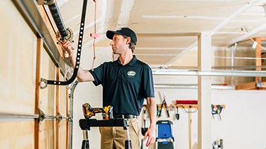 Precision Garage Door tech on ladder fixing door.