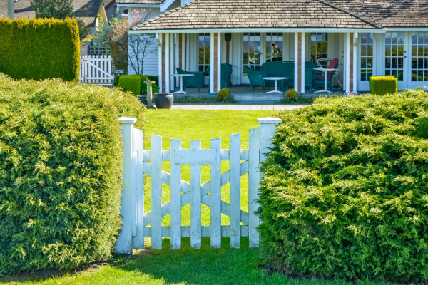 Home with a white gate, green lawn, and beautiful front yard patio.