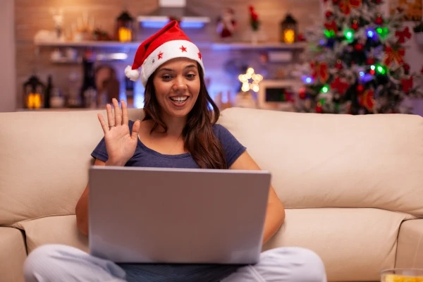 Young woman using a laptop on her couch with holiday decoration in the background.