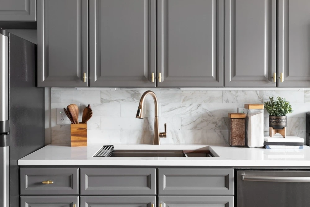kitchen sink with grey cabinets and gold hardware.